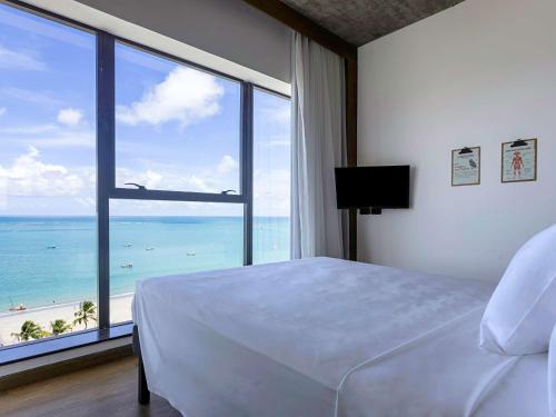 a bedroom with a bed and a large window with the ocean at ibis Styles Maceió Pajuçara in Maceió