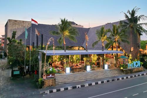 un ristorante sul lato di un edificio con palme di THE 1O1 Bali Oasis Sanur a Sanur