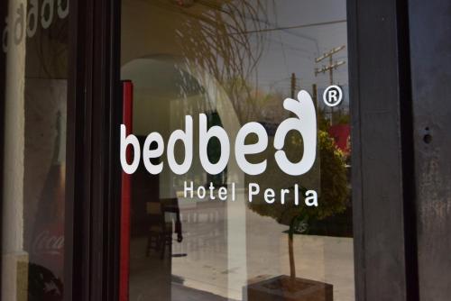 un cartello su una porta a vetri di un hotel Pera di Bed Bed Hotel Perla a Torreón