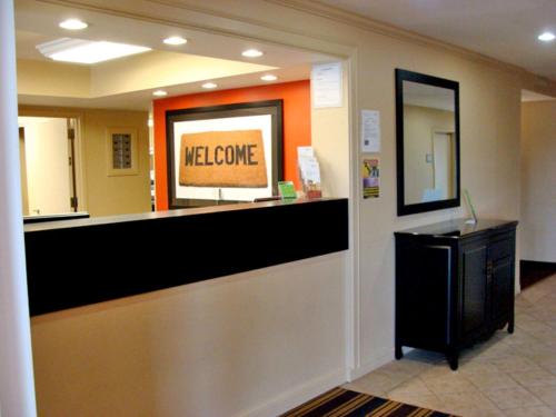 - un comptoir de bienvenue dans le hall avec un panneau de bienvenue dans l'établissement Extended Stay America Suites - Meadowlands - East Rutherford, à East Rutherford