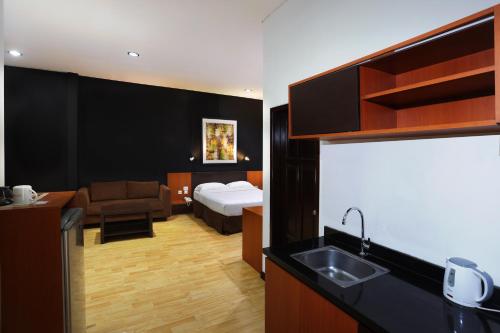 een hotelkamer met een bed en een keuken met een wastafel bij Jambuluwuk Residence Menteng in Jakarta