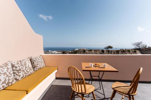 - un balcon avec un banc, une table et des chaises dans l'établissement Perla Nera Suites, à Fira