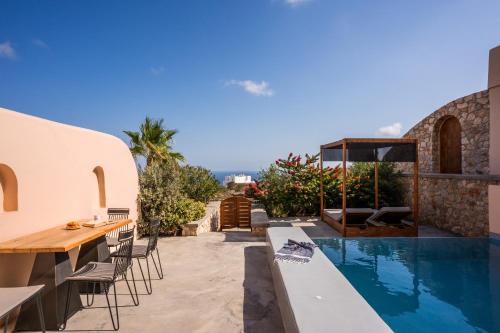 un patio extérieur avec une table et des chaises ainsi qu'une piscine dans l'établissement Perla Nera Suites, à Fira