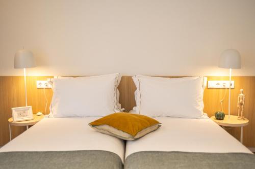 a bed with white sheets and a brown pillow on it at Watts House in Seia