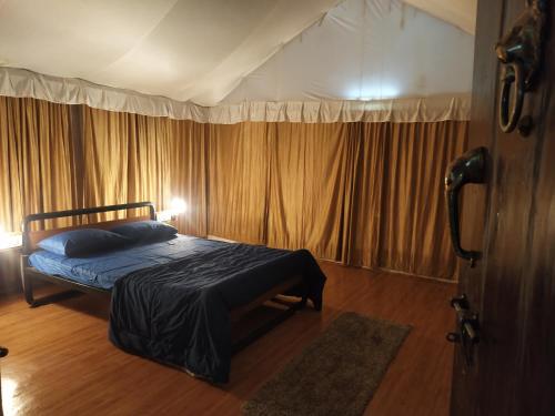 a bedroom with a bed in a room with curtains at Trident Jungle Stay in Dandeli