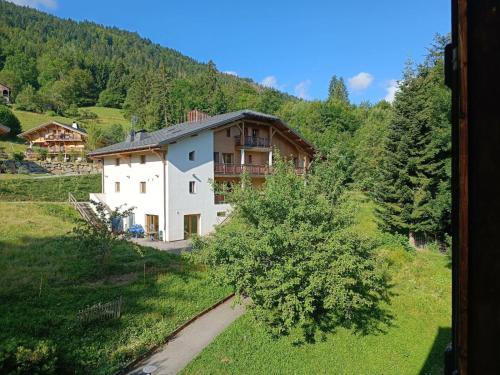 ein Haus mitten auf einem grünen Feld in der Unterkunft Chalet d'Arfeuille - Chambre 2 personnes in Samoëns