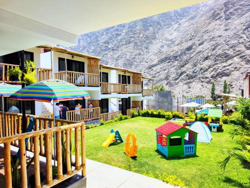 un cortile con parco giochi con una montagna sullo sfondo di Jalara Lunahuaná Hotel a Lunahuaná