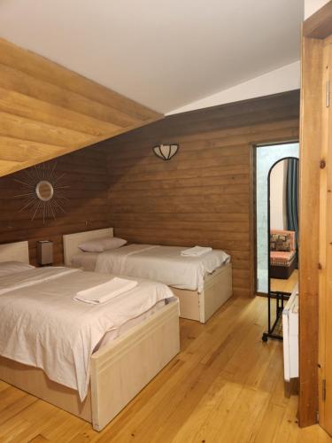 two beds in a room with wooden walls at Sanli in Mestia