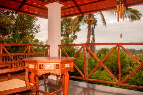 a wooden table on a porch with a palm tree at Over The Hill in Pūvār