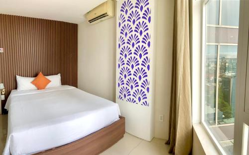 1 dormitorio con cama blanca y ventana en Pariat River Front Hotel, en Da Nang