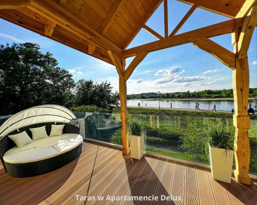 um deque de madeira com uma cadeira e vista para um lago em Bulwar Residence & Wellness em Kazimierz Dolny