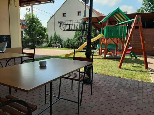 patio con mesa y parque infantil con tobogán en Gyulai Meseház Apartman, en Gyula