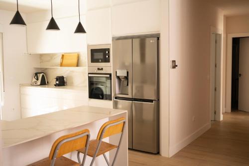 a kitchen with a stainless steel refrigerator and two chairs at Apartamento NUEVO en el centro de LEON in León