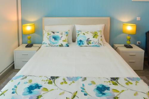 a bedroom with a large white bed with blue flowers at Holidays Nazaré marginal in Nazaré