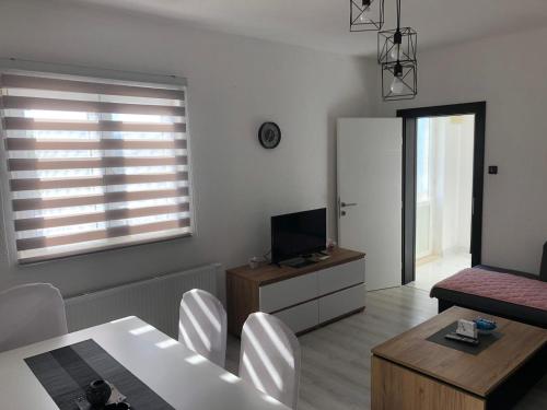 een woonkamer met een tafel en stoelen en een televisie bij Apartman M&D in Neum