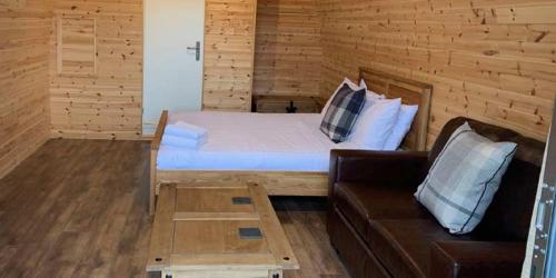 Cette chambre en bois comprend un lit et un canapé. dans l'établissement Superior Glamping Pod with Hot Tub, à Frodsham