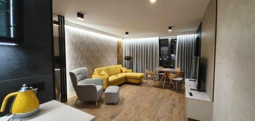 uma sala de estar com um sofá amarelo e uma mesa em Apartamenty IMPRESSA BASEN - SPA - SAUNA Lublin Centrum em Lublin