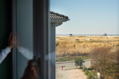 una persona che guarda fuori dalla finestra di un campo di Beach Motel St. Peter-Ording a Sankt Peter-Ording