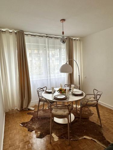 ein Esszimmer mit einem Tisch, Stühlen und einem Fenster in der Unterkunft Appartement neuf à boulogne à 3 mins à pieds du métro in Boulogne-Billancourt