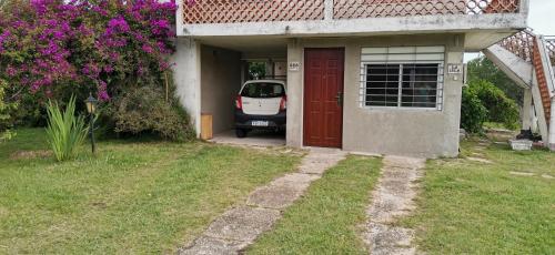 een auto geparkeerd buiten een huis met een rode deur bij La Isla - Araminda in Balneario Argentino