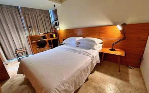 1 dormitorio con 1 cama blanca grande y cabecero de madera en Zhuhai Bei Shan Ju Art Hotel, en Zhuhai