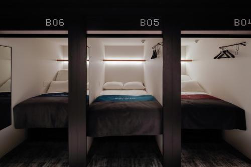 two twin beds in a small room with twothirds at The Millennials Kyoto in Kyoto