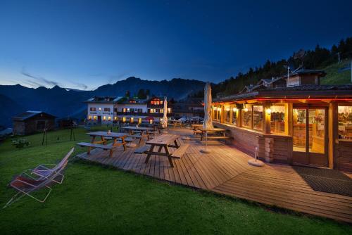 een houten terras met tafels en stoelen in een gebouw bij Hotel Gallo Cedrone in Valdisotto