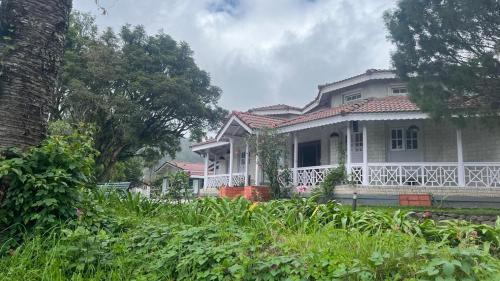 a large white house with a large porch at Bruton resorts in Kodaikānāl