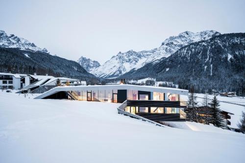 een huis in de sneeuw met bergen op de achtergrond bij Paramount Alma Suites in Sesto