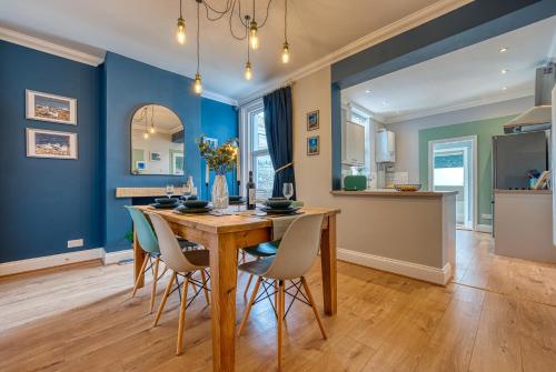 una sala da pranzo con pareti blu e tavolo e sedie in legno di XMAS SPECIAL OFFER!! 2-BR Modern, Stylish & Stunning Contractor House, Prime Portsmouth Location with Parking - By Blue Puffin Stays a Portsmouth