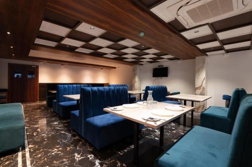 a dining room with blue chairs and a table at Hotel Vilvah in Coimbatore