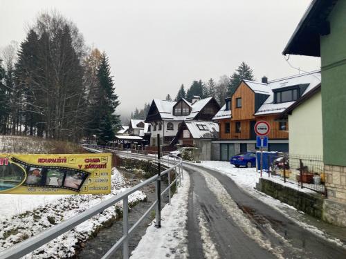 une rue enneigée dans une ville avec des maisons dans l'établissement Harrachov 702, à Harrachov