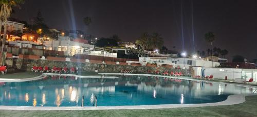 ein Pool mit roten Stühlen und Gebäuden in der Nacht in der Unterkunft Relax in pasito blanco camping house in Maspalomas