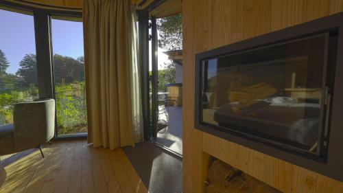 Cette chambre dispose d'une télévision sur le côté d'un mur. dans l'établissement Cabanes avec jacuzzi les pieds dans la vignes, 