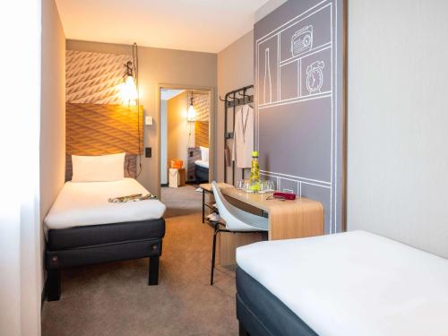 um quarto de hotel com duas camas e uma secretária em ibis Geneve Centre Lac em Genebra