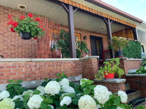 uma casa de tijolos com flores em frente em Havre chez Guylaine em Laval