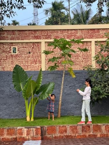 a woman and a child standing next to a tree at Easy Inn Wayanad in Kaniyāmbetta