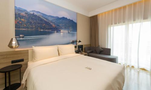 een hotelkamer met een groot bed en een groot raam bij Atour Hotel Chongqing Hongyadong Riverview in Chongqing