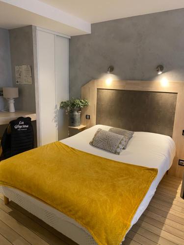 um quarto com uma cama grande e um cobertor amarelo em La glycine hotel et spa em Bénouville