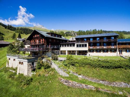 un grand bâtiment sur une colline avec un champ verdoyant dans l'établissement Hotel Restaurant Capricorns, à Wergenstein