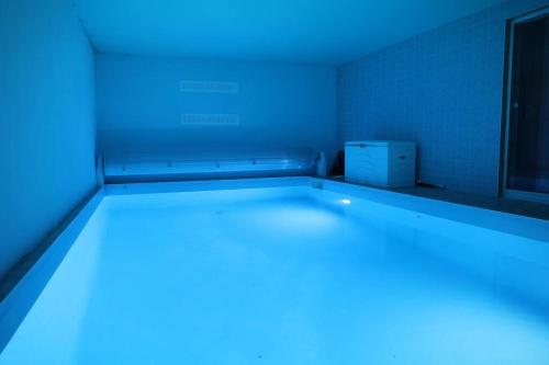 ホルツハイムにあるVilla avec piscine intérieureの青い照明が付いたベッドが備わる客室です。