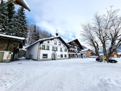 a snow covered street with a white house at Hotel & Gasthof Taferne in Schladming