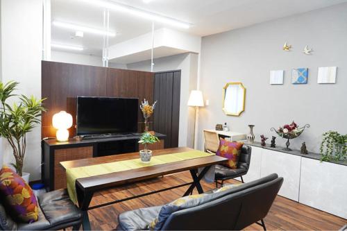 uma sala de estar com uma mesa e algumas cadeiras em TORII room em Kumamoto