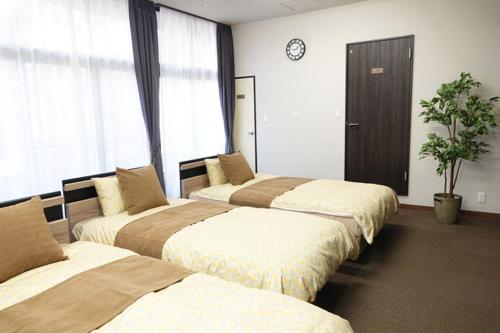 um quarto de hotel com três camas e um relógio na parede em TORII room em Kumamoto