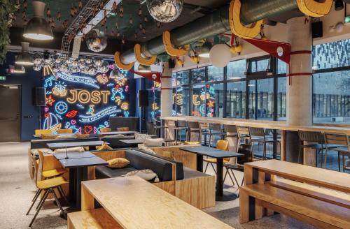 un restaurante con mesas y sillas de madera y un mural en JOST Hôtel Le Havre Centre Gare, en Le Havre