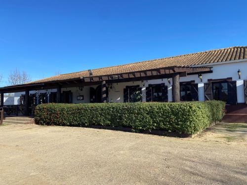 un edificio con un seto delante de él en Camping La Aldea, en El Rocío