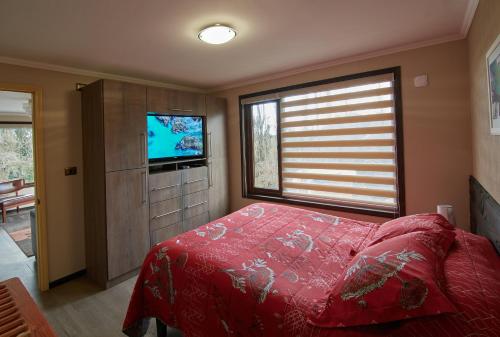 um quarto com uma cama vermelha e uma televisão em mirabosque new aparments 4 em Osorno