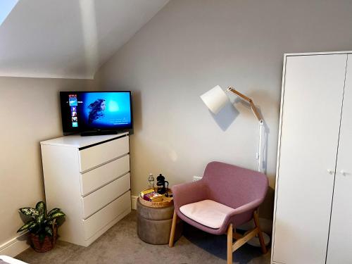 uma sala de estar com uma cadeira e uma televisão em Lakeside LUX bedroom with parking, M4 Jct 11, next to train station em Reading