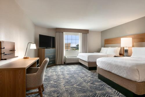 ハリスバーグにあるCandlewood Suites Harrisburg I-81 Hershey Area by IHGのベッド2台、デスク、テレビが備わるホテルルームです。