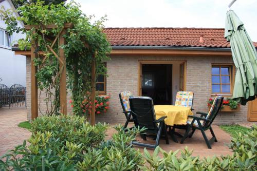 um pátio com uma mesa, cadeiras e um guarda-sol em Ferienhaus Weingarten em Bad Fallingbostel